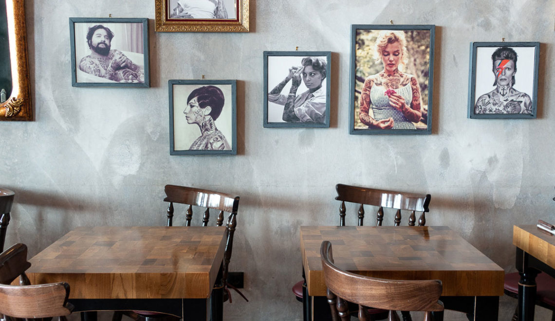 two tables with chairs and portraits on the wall
